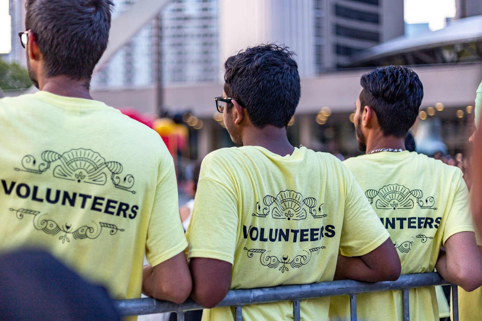 Three volunteers in matching yellow Volunteers shirts standing together, ready for an outreach — the kind of team a nonprofit needs to sign up and schedule without losing track