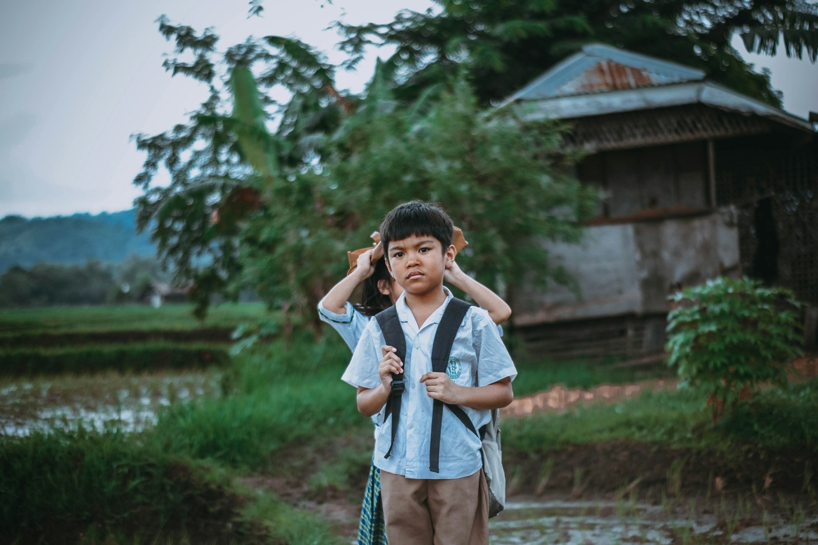Two Filipino students walking outdoors, one carrying a backpack